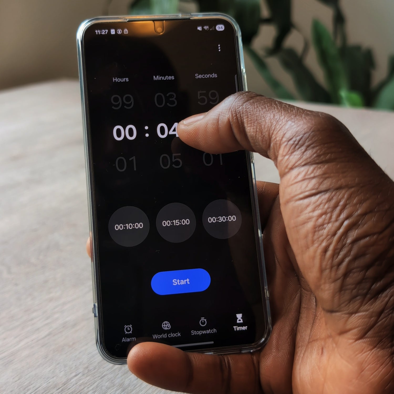 Hand holding a smartphone with a timer app on the screen, set to 4 minutes.